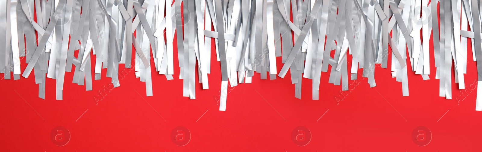Image of Silver tinsel on red background, top view. Banner design