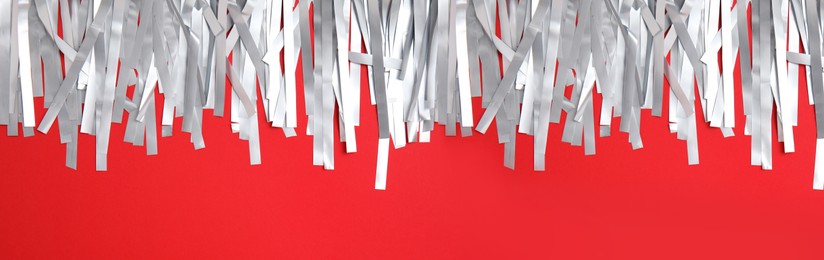 Image of Silver tinsel on red background, top view. Banner design