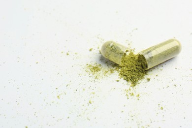 Photo of Broken light green vitamin capsule on white background, closeup. Space for text