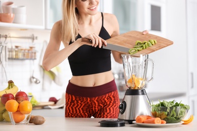 Photo of Young woman preparing tasty healthy smoothie at table in kitchen