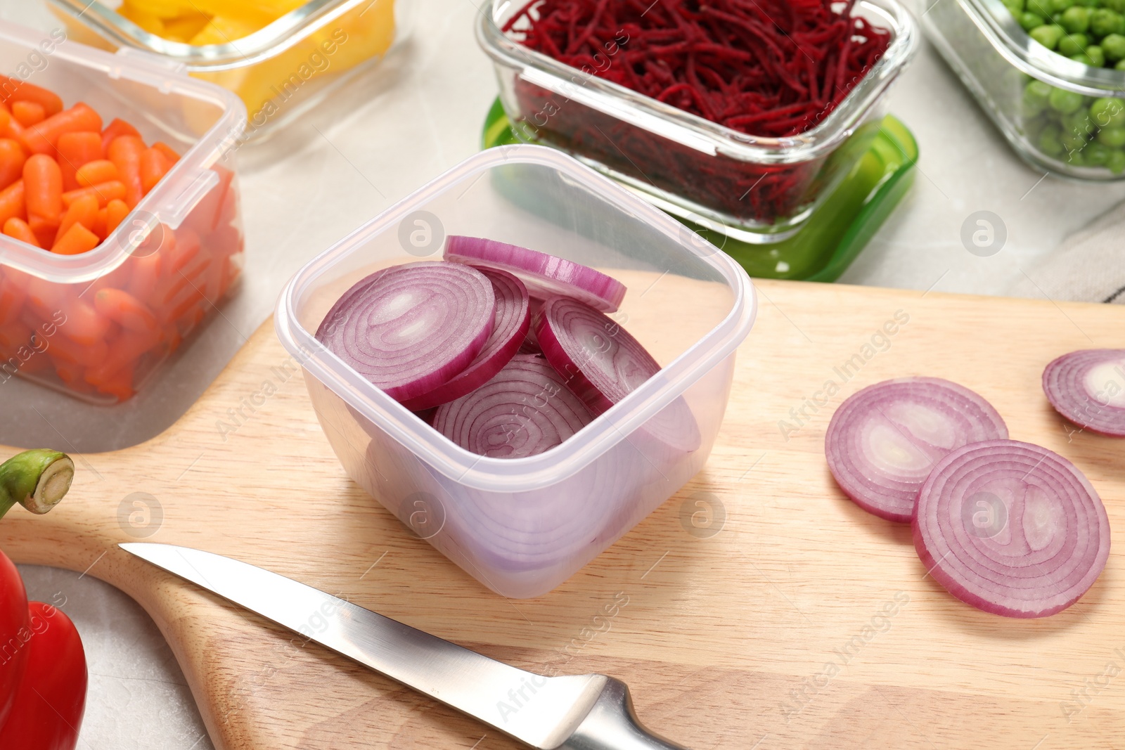 Photo of Containers with cut onion and fresh products on table. Food storage
