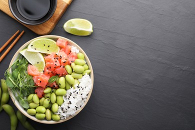 Photo of Delicious poke bowl with lime, fish and edamame beans on black table, flat lay. Space for text