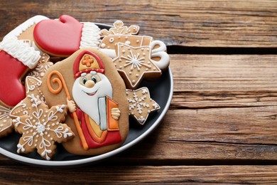 Photo of Tasty gingerbread cookies on wooden table, closeup and space for text. St. Nicholas Day celebration