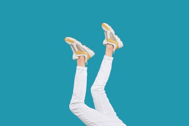 Photo of Woman in stylish sport shoes on light blue background