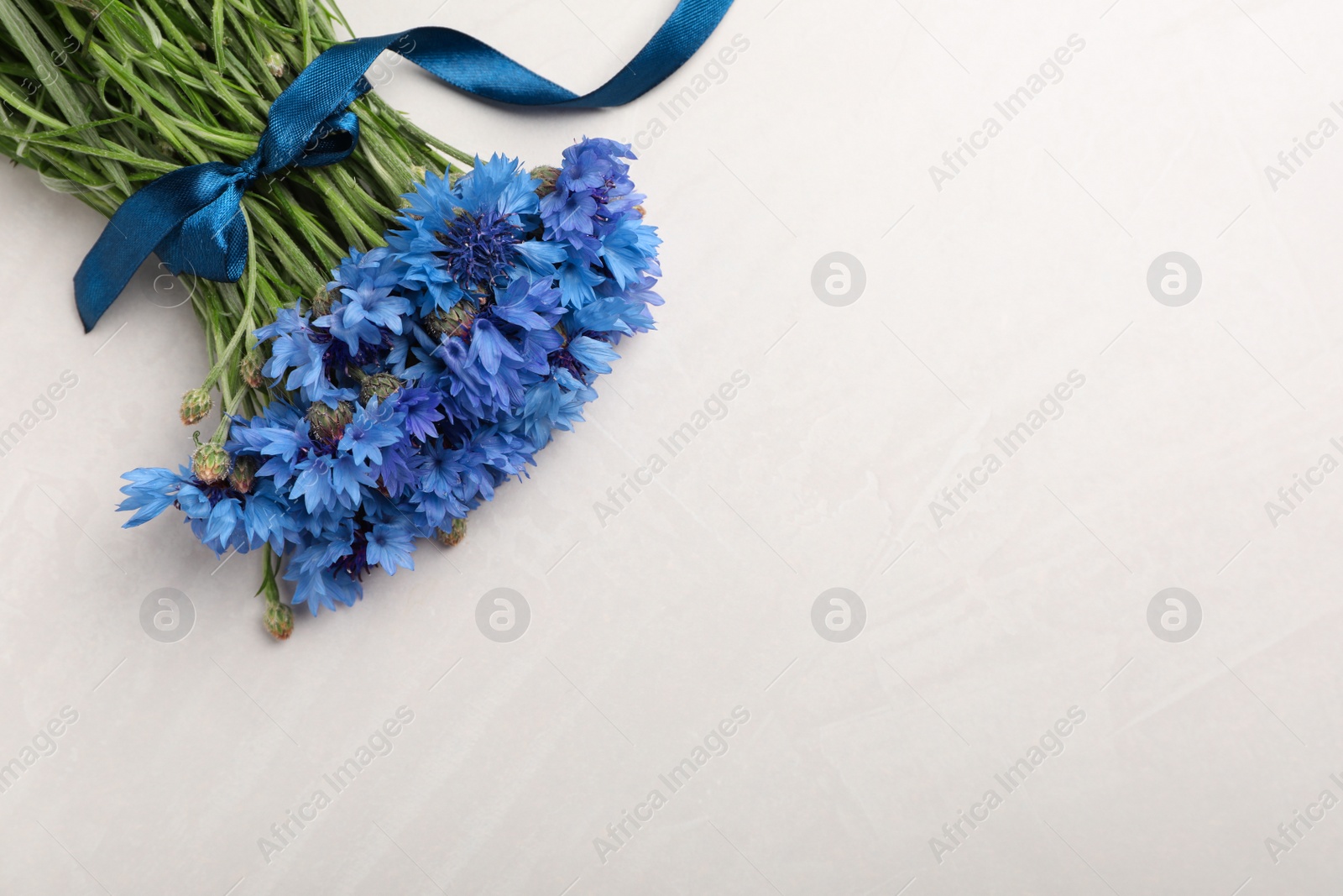 Photo of Bouquet of beautiful cornflowers on light table, top view. Space for text