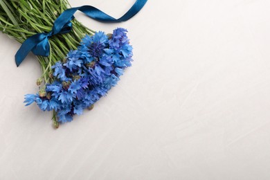 Photo of Bouquet of beautiful cornflowers on light table, top view. Space for text