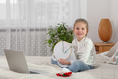 Little girl learning to embroider with online course at home. Space for text