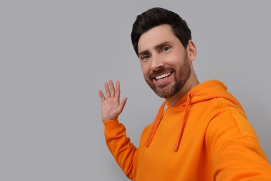 Photo of Smiling man taking selfie on grey background, space for text