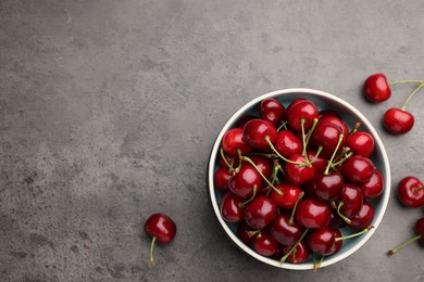 Bowl with ripe sweet cherries on grey table, flat lay. Space for text