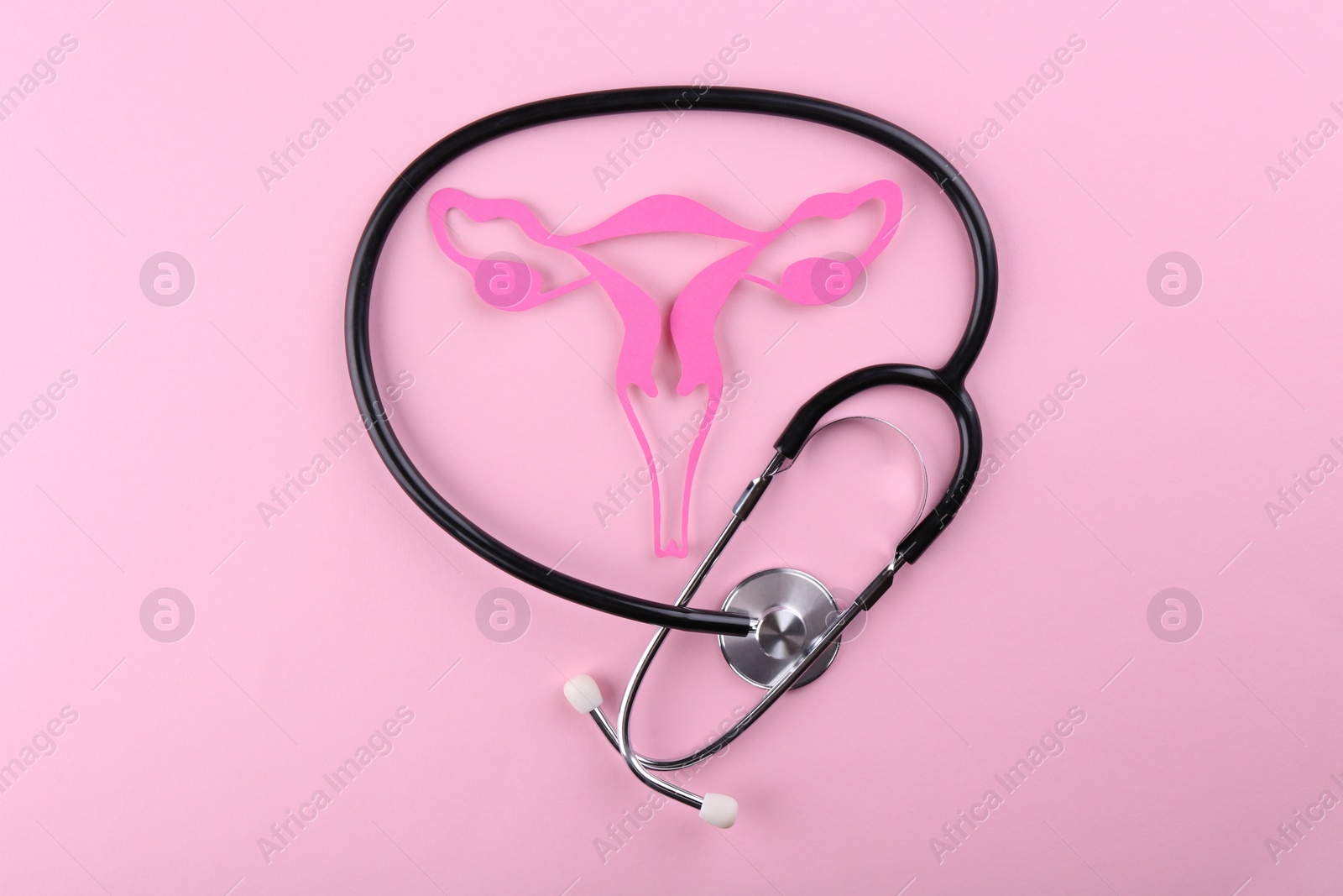 Photo of Reproductive medicine. Paper uterus and stethoscope on pink background, top view