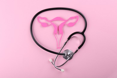 Reproductive medicine. Paper uterus and stethoscope on pink background, top view