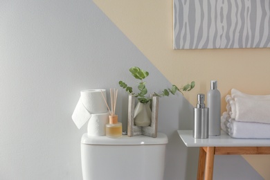 Table and toilet bowl with decor elements and necessities near color wall. Bathroom interior