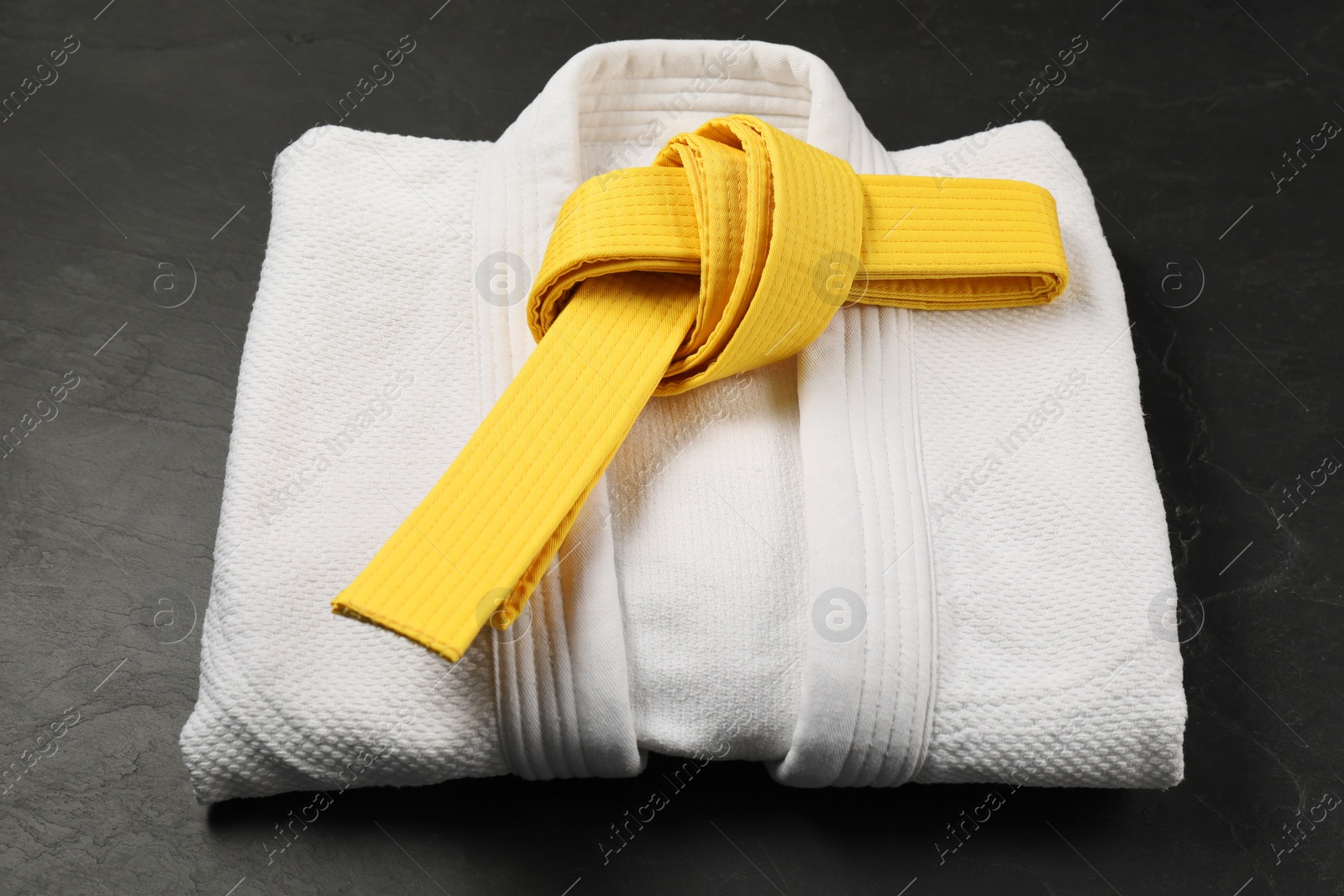 Photo of Yellow karate belt and white kimono on gray background