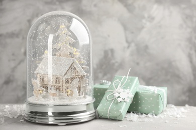 Photo of Beautiful Christmas snow globe and gift boxes on light table