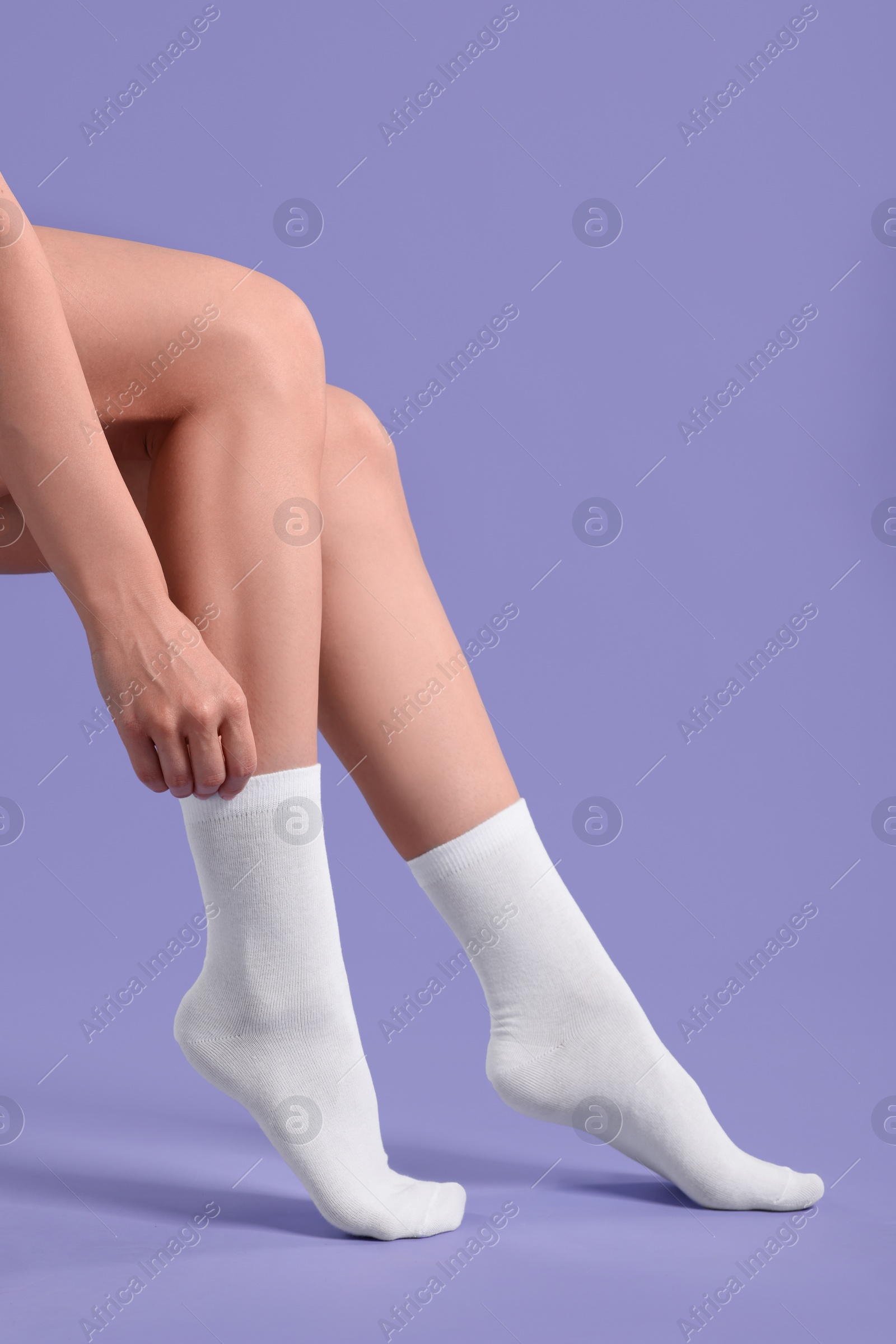 Photo of Woman in stylish white socks on violet background, closeup