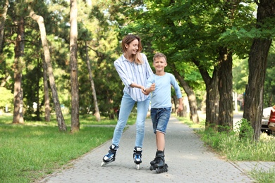 Mother and son roller skating in summer park
