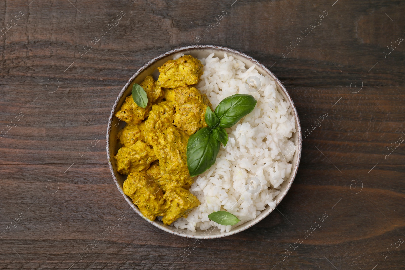 Photo of Delicious rice and chicken with curry sauce on wooden table, top view