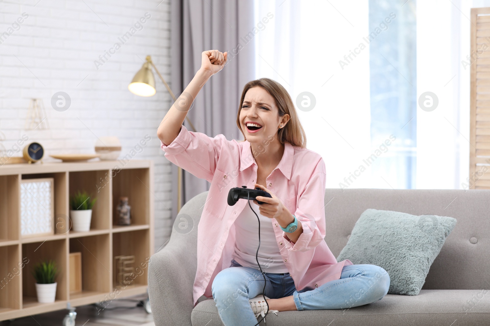 Photo of Emotional young woman playing video game at home