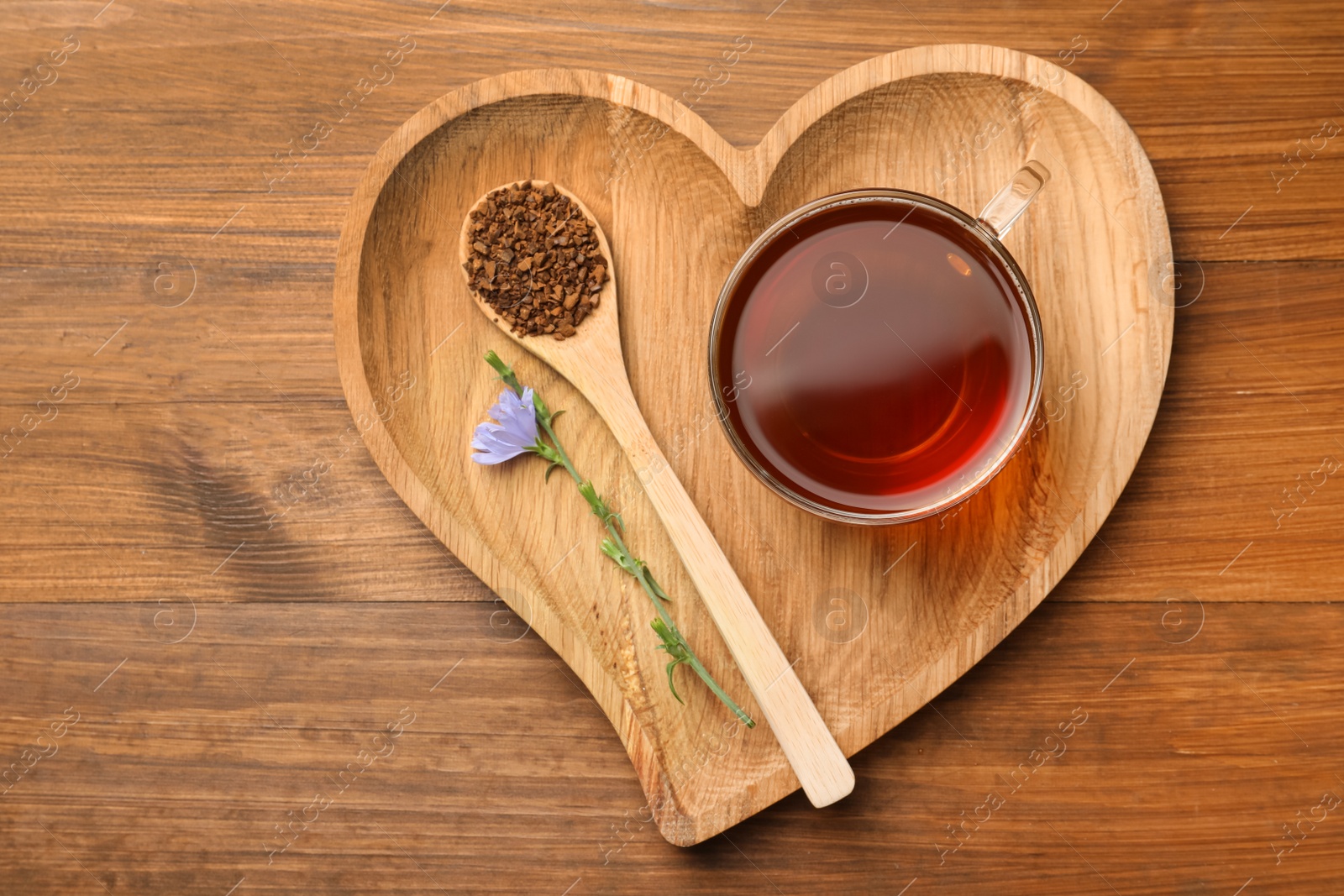 Photo of Cup of delicious chicory drink, granules and flower on wooden table, top view