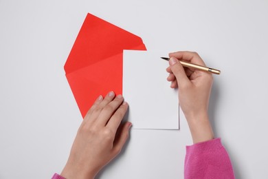 Woman writing letter at white table, top view. Space for text