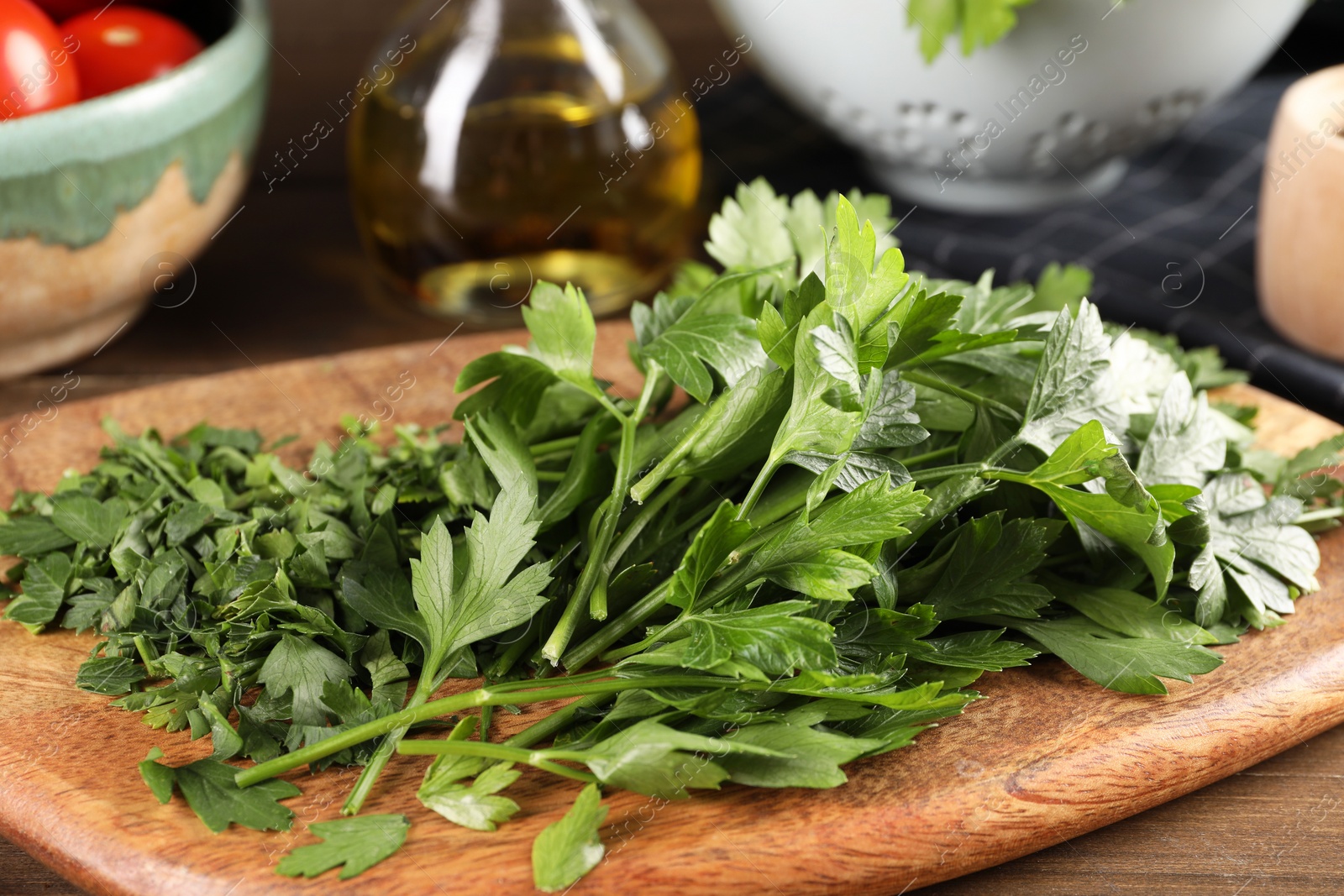 Photo of Wooden board with fresh green parsley on table, closeup