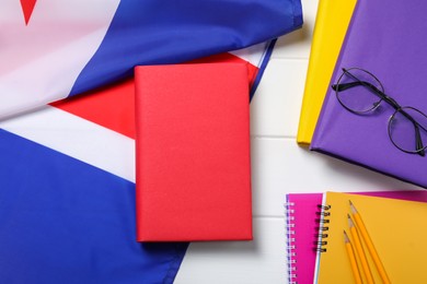 Photo of Learning foreign language. Flag of United Kingdom, books, stationary and glasses on white table, flat lay