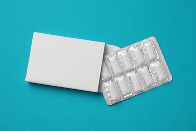 Photo of Pack with tasty chewing gums on turquoise background, top view