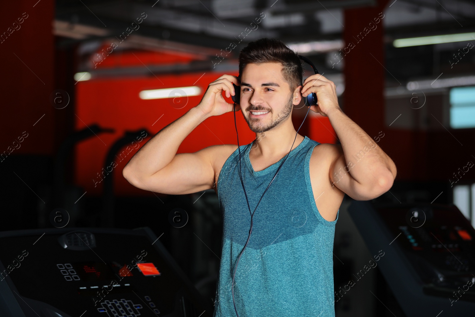 Photo of Young man listening to music with headphones at gym