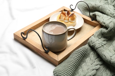 Composition with coffee and warm plaid on white bedsheet