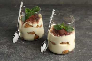 Delicious tiramisu with mint in glasses on grey table