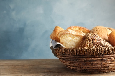 Basket with fresh bread on table against color background. Space for text