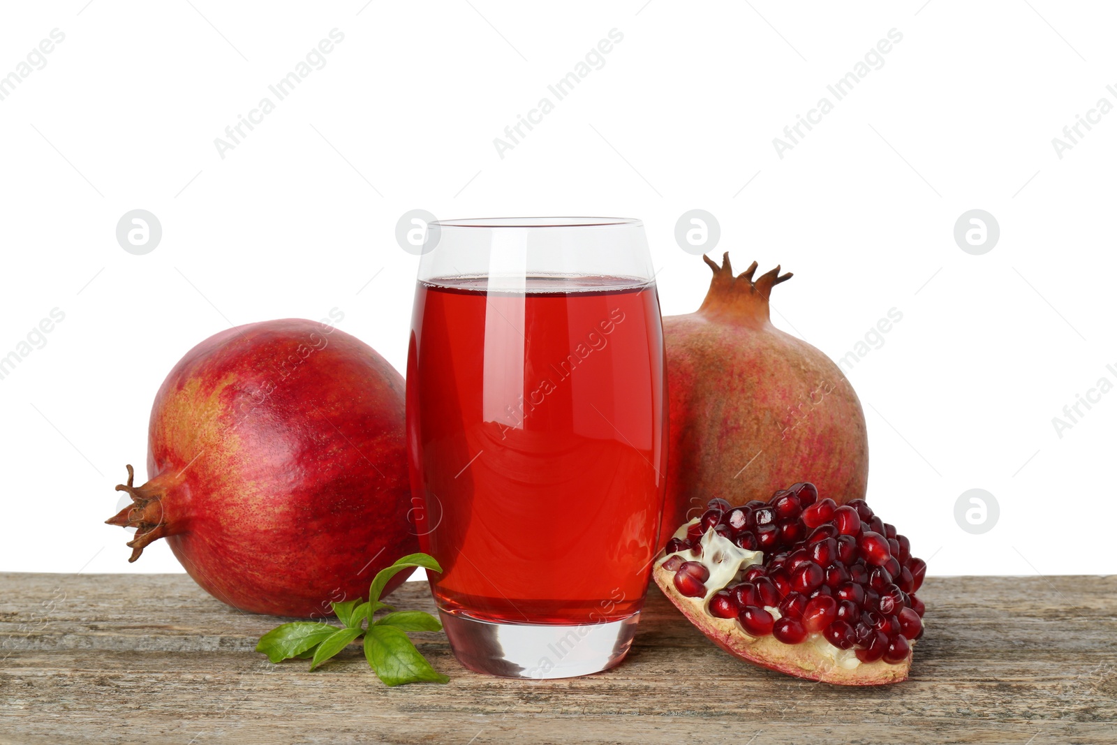 Photo of Refreshing pomegranate juice in glass, leaves and fruits on wooden table against white background