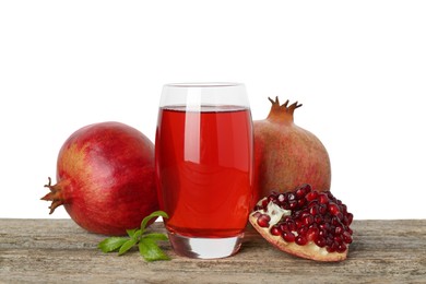 Photo of Refreshing pomegranate juice in glass, leaves and fruits on wooden table against white background