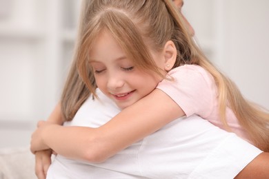 Photo of Little girl hugging her grandmother on blurred background, closeup