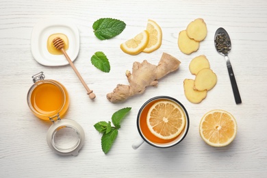 Composition with cup of lemon tea, ginger and honey on wooden background, top view