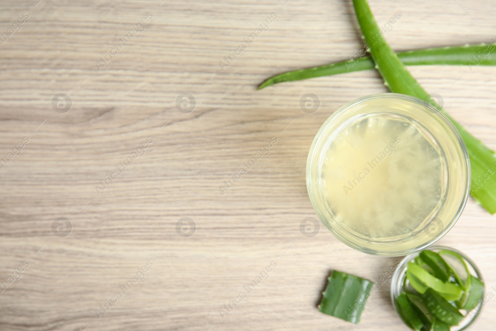 Photo of Fresh aloe drink in glass and leaves on wooden table, flat lay. Space for text