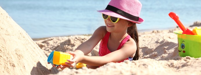 Image of Cute little child playing with plastic toys at sandy beach on sunny day. Banner design