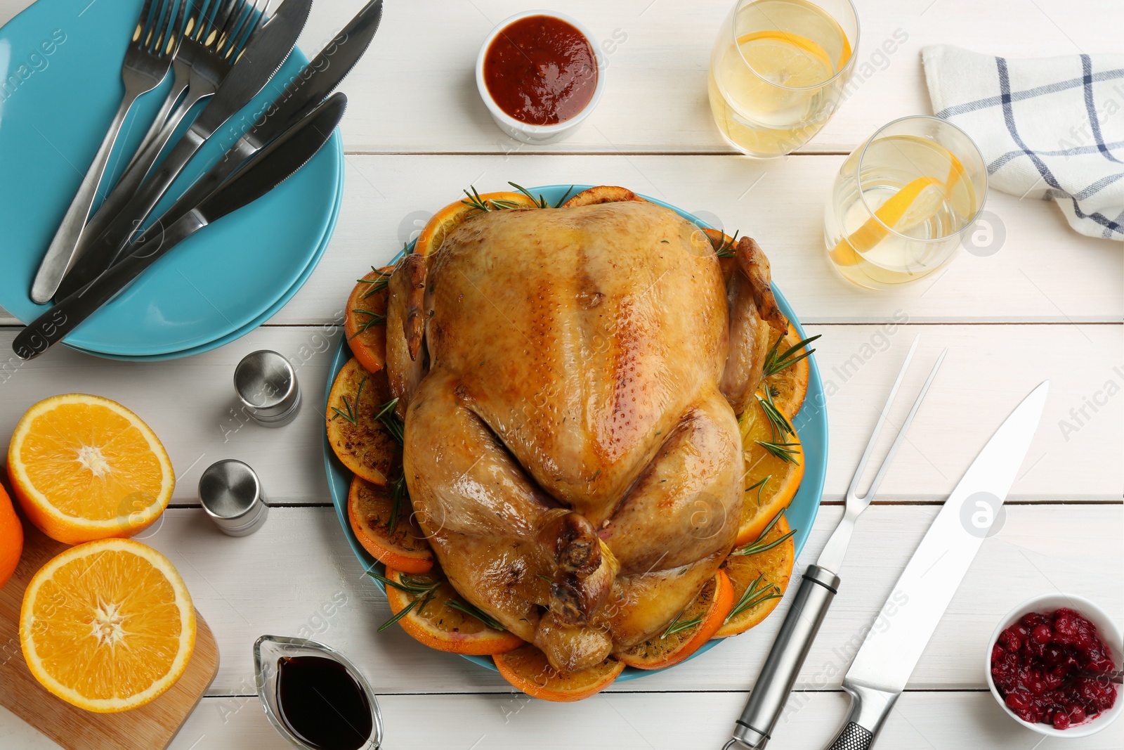 Photo of Delicious chicken with oranges and rosemary on white wooden table, flat lay