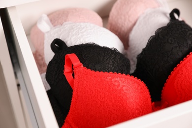 Photo of Drawer with beautiful lace bras, closeup. Stylish underwear