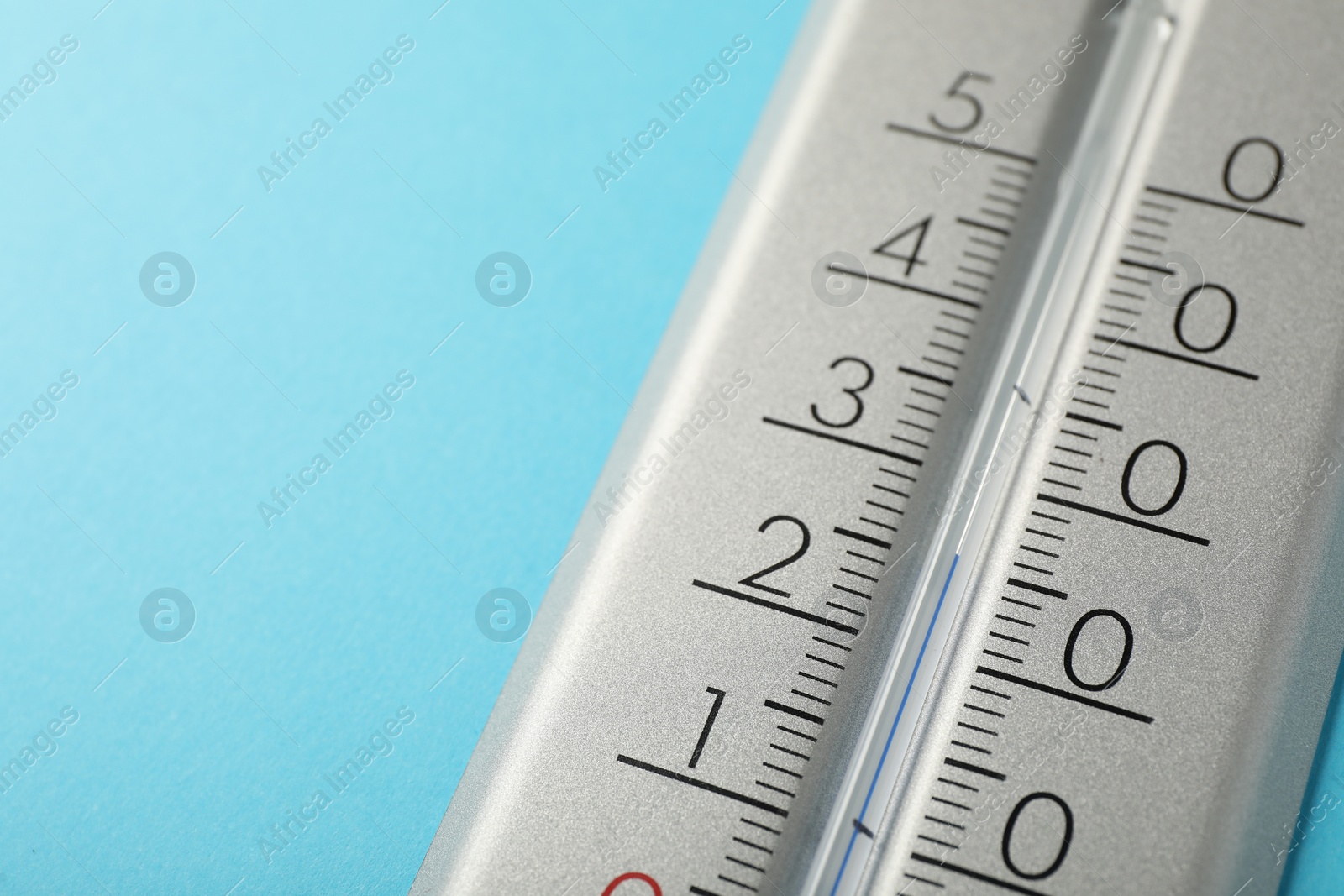 Photo of Weather thermometer on light blue background, closeup. Space for text