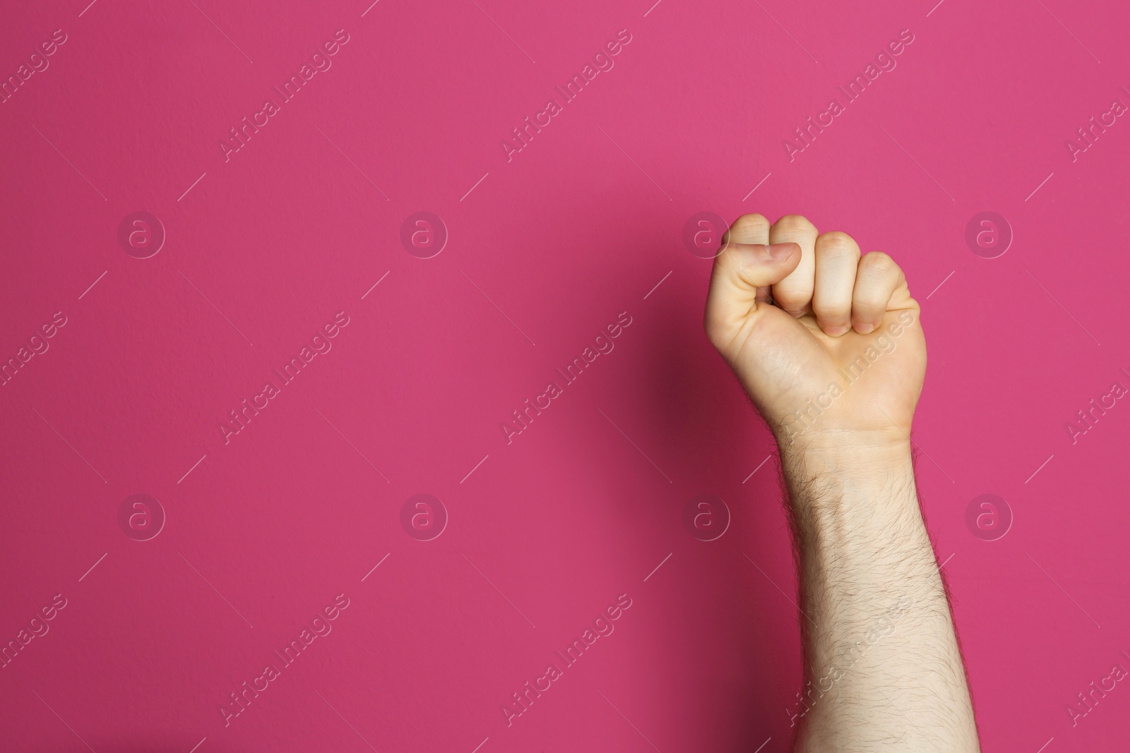 Photo of Young man showing clenched fist on color background. Space for text