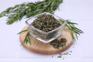 Photo of Dry and fresh tarragon on white tiled table