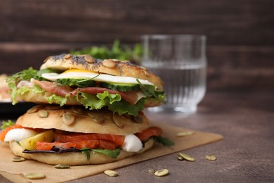 Stacked tasty bagel sandwiches on brown table, closeup. Space for text