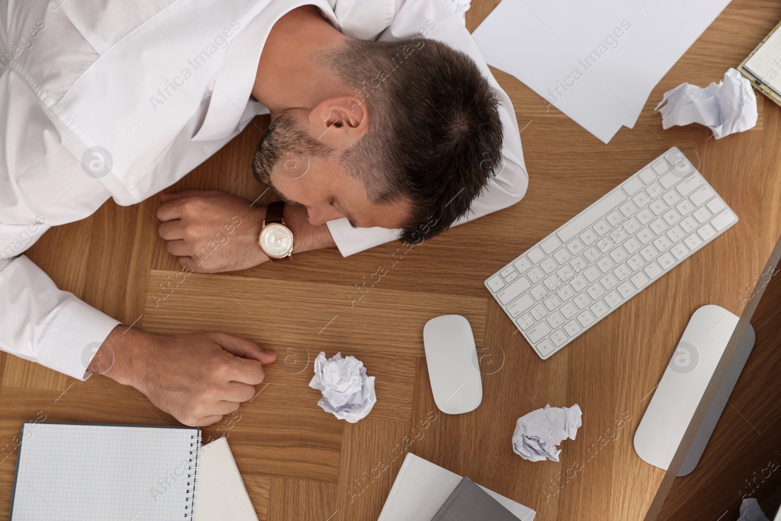 Photo of Tired man sleeping at workplace, top view