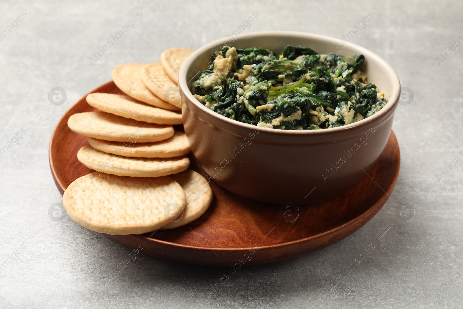 Photo of Tasty spinach dip with egg and crackers on grey table, closeup