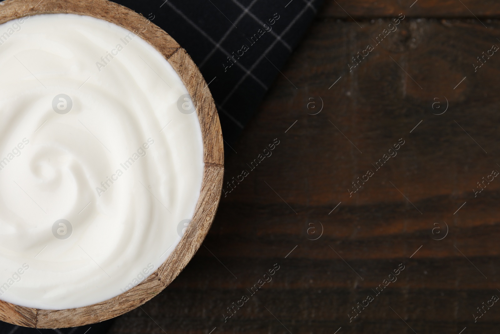 Photo of Delicious natural yogurt in bowl on wooden table, top view. Space for text