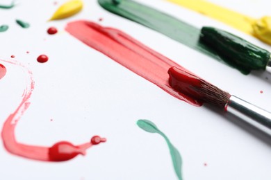 Photo of Brushes with different paints and strokes on white background, closeup