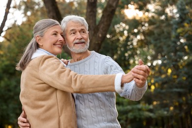 Photo of Affectionate senior couple dancing together outdoors. Romantic date