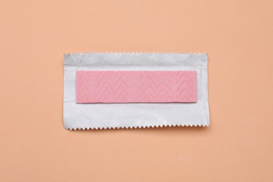 Unwrapped stick of chewing gum on coral background, top view