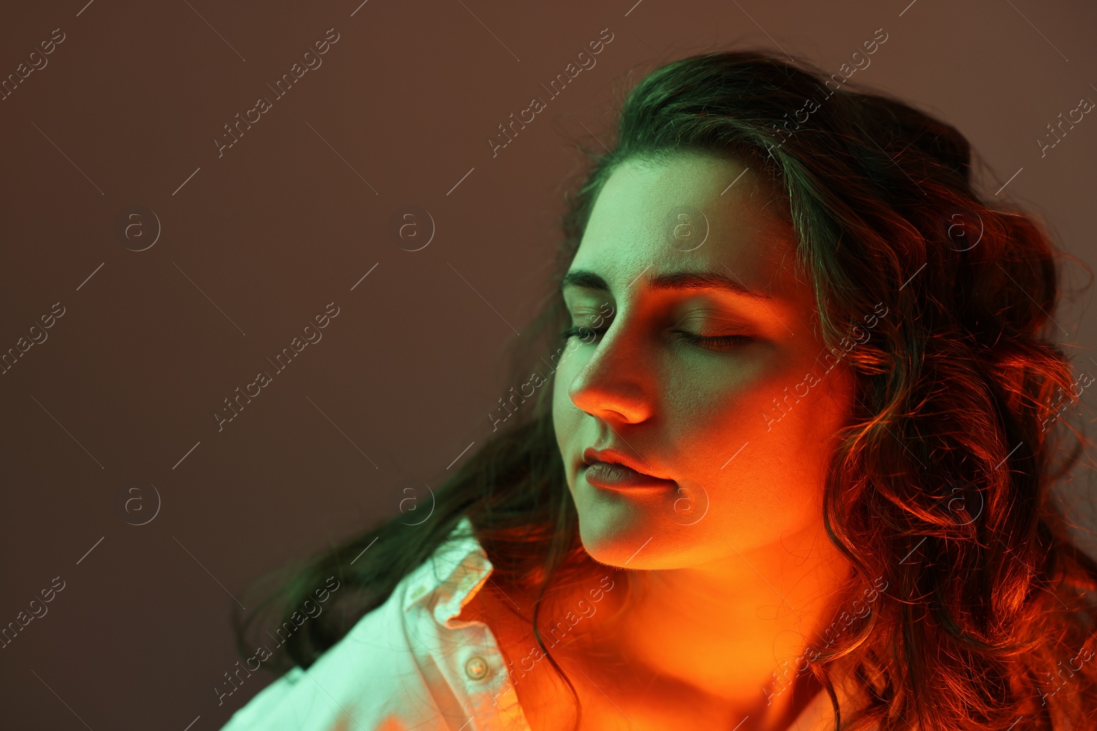 Photo of Portrait of beautiful young woman on color background with neon lights, space for text